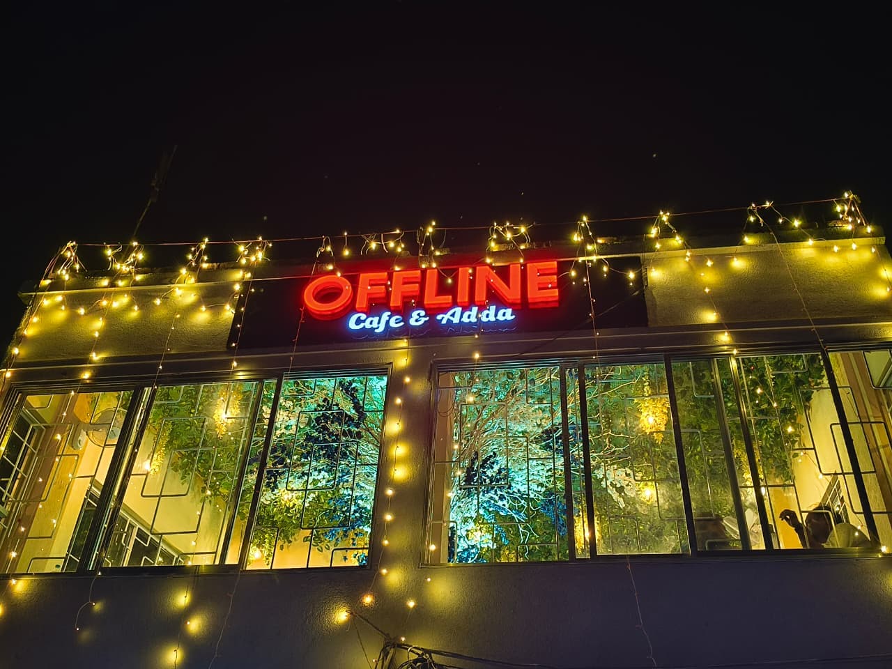 Offline Cafe & Adda at night — neon signboard and fairy lights
